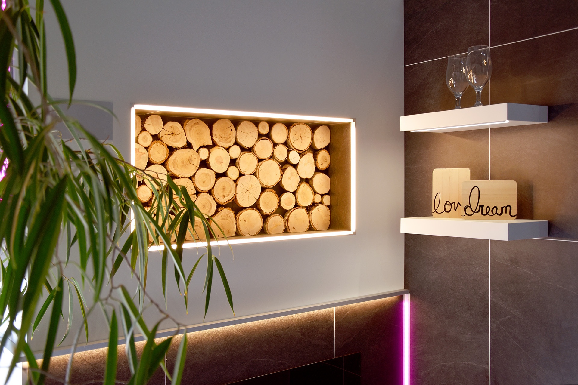 Beleuchtete Wandnische mit dekorativen Holzscheiten und indirekter LED-Lichtleistung.