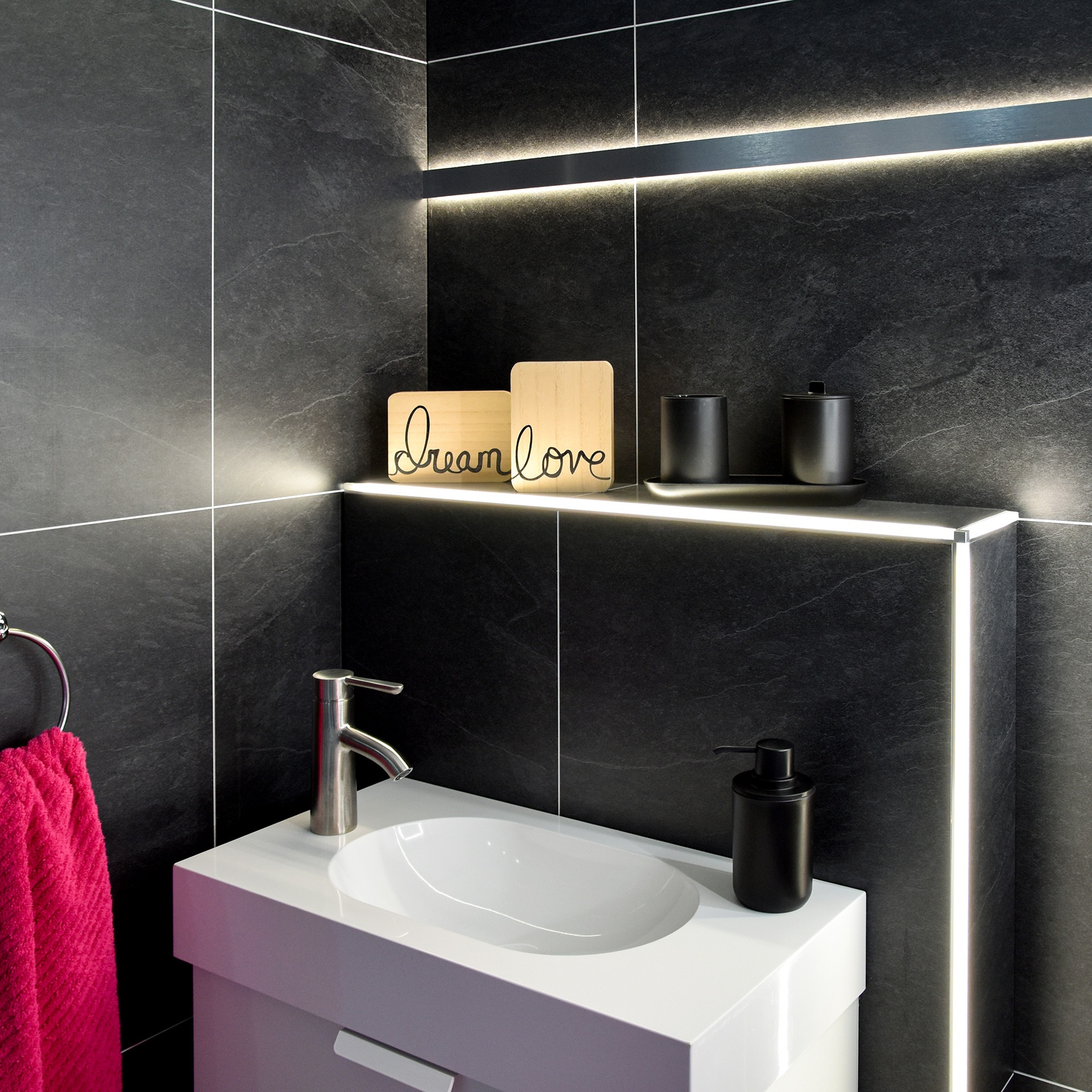 Modernes Badezimmer mit dunklen Schieferfliesen und LED-Lichtleisten als Akzentbeleuchtung am Waschtisch.